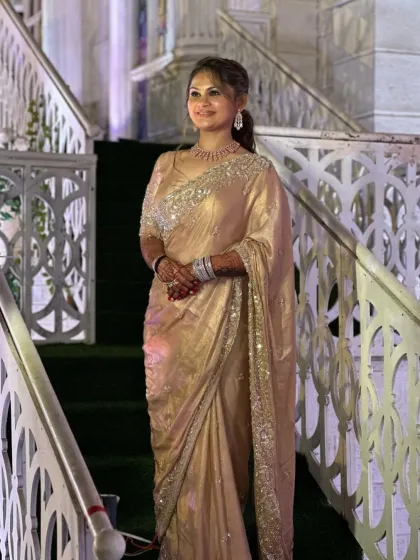 A full-length shot of the client on a grand staircase, looking absolutely elegant in her golden saree.