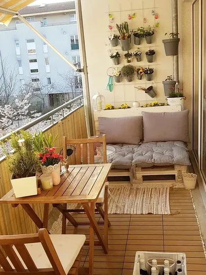 This cozy balcony uses wooden pallets to create a custom sofa, paired with a simple wooden table and flooring. The wall-mounted planters are a great space-saving solution for adding greenery.