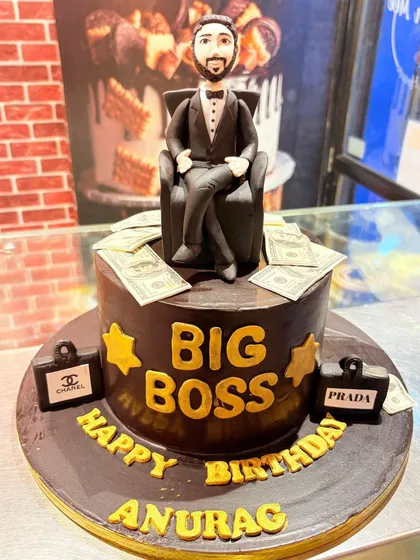A "Big Boss" themed cake for Anurag, featuring a fondant figurine sitting on a throne of money, with mini Chanel and Prada briefcases.