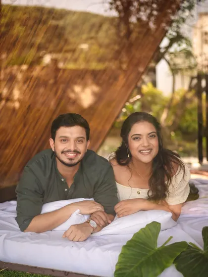 A happy, smiling portrait of the couple during their cabin-themed pre-wedding shoot. Their relaxed, coordinated outfits in earthy tones perfectly match the natural and cozy setting.