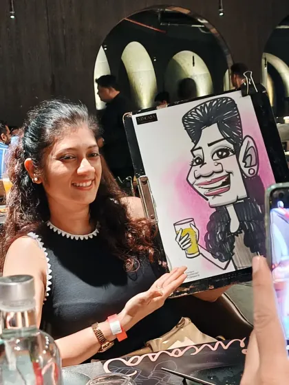 A guest proudly showing off her caricature while her friend takes a picture. It's an interactive and social experience.