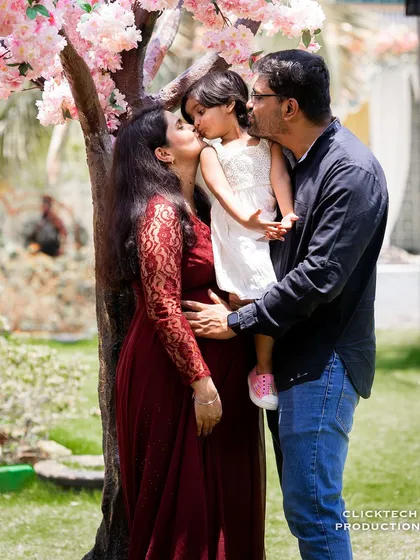 A sweet and loving family photograph where both parents kiss their daughter. This image beautifully captures the bond of the existing family unit as they await their new arrival.