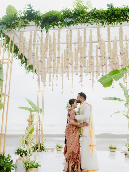 A tender kiss on the forehead at their beachside South Indian wedding. The mandap, adorned with jasmine and banana leaves, beautifully frames this moment of blessing and love.
