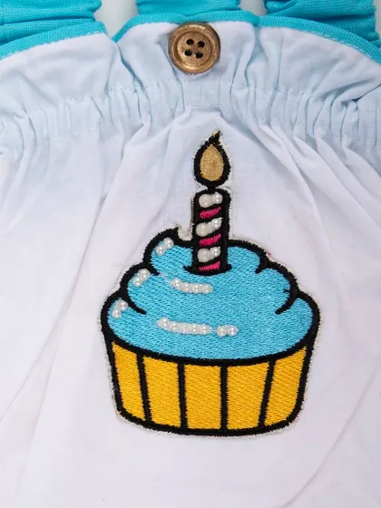 A close-up of the blue cupcake embroidery on a baby romper.
