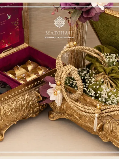 Two distinct Rajwada Boxes, showcasing their versatility. One is filled with gourmet treats and a personalized scroll, while the other is styled as a basket, demonstrating how these chests can be adapted for various wedding gifting needs.
