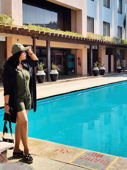 Poolside relaxation in an olive green romper and a black cover-up. This is a perfect example of a resort wear look that is both stylish and practical.