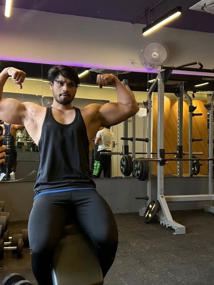 Seated double bicep pose on a bench, showcasing arm size and conditioning.