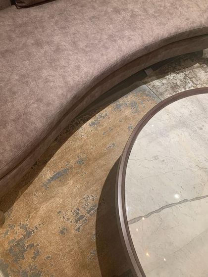 The gentle curve of a sofa meets the clean circle of a marble-topped table, a simple composition of contrasting forms.