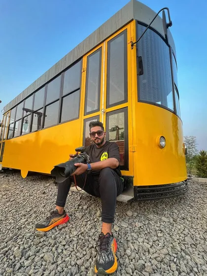 A wide shot of me with my gear in front of the yellow tram, showcasing a fun shooting location.