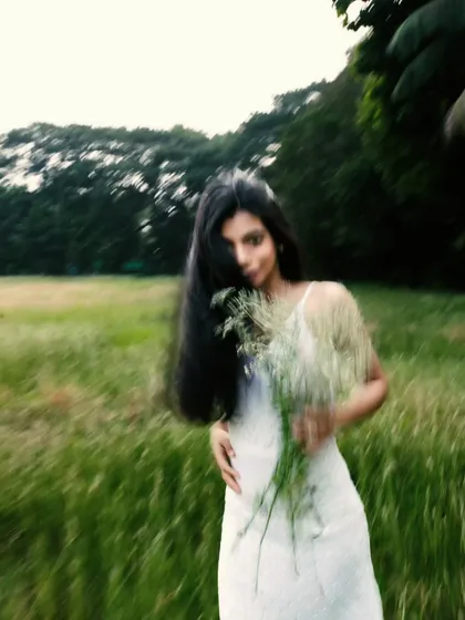 A playful, partially obscured portrait, using a bouquet of wildflowers to add a touch of whimsy and a soft, blurry foreground.