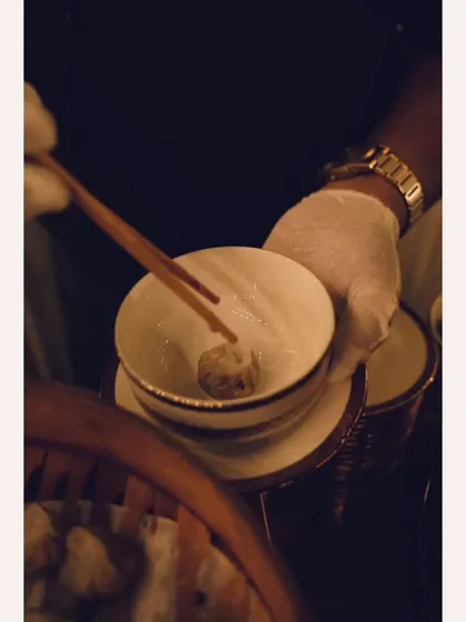 A guest enjoying a freshly steamed dim sum with chopsticks. My interactive stations allow guests to savor authentic flavors and experiences.
