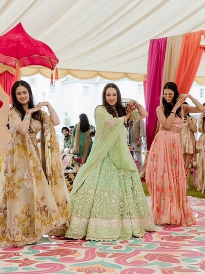 A graceful bridesmaid performance at a daytime Mehendi in London. The colorful floral floor and pastel outfits create a beautiful, garden-party atmosphere.