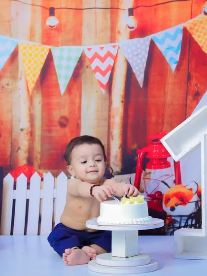 The moment before the smash. The birthday boy curiously pokes at his cake, ready to begin the celebration.