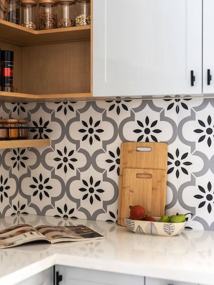 A detail shot of the kitchen countertop, showing the elegant tile backsplash and the warmth of the wooden cutting boards.