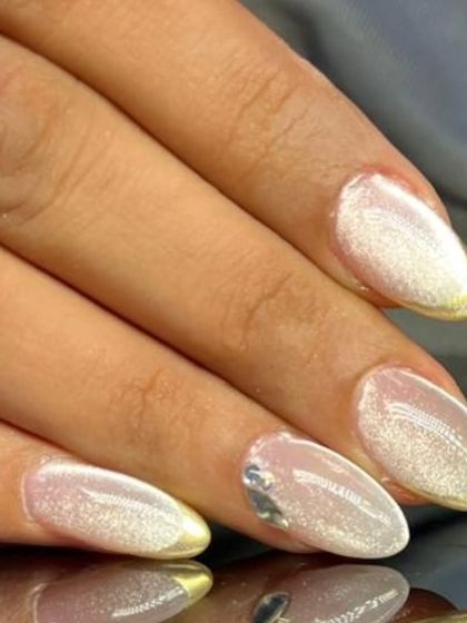 A close-up of the luxurious gold chrome and cat-eye French manicure, showing the beautiful light reflection.