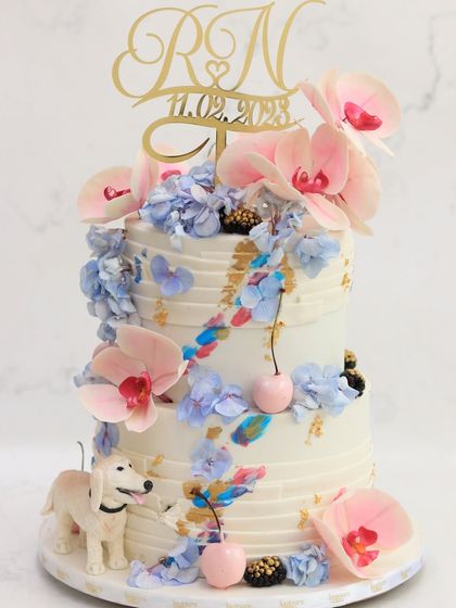 Your cake should be personal, right down to the last detail. This custom wedding cake includes a charming, handcrafted figurine of the couple's beloved dog, alongside beautiful sugar orchids and hydrangeas.