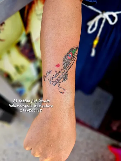 A "Radha Krishna" tattoo design with a peacock feather and flute.
