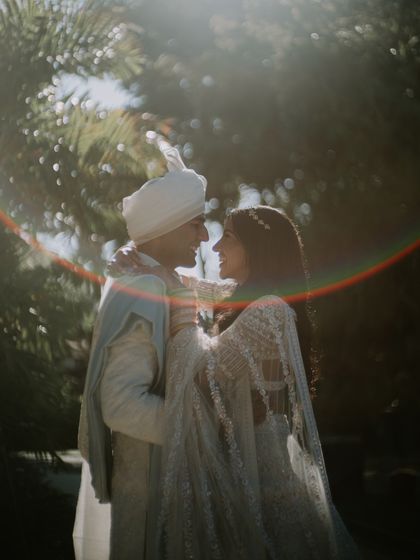 A dreamy, sun-kissed moment from their Bali wedding. The bride's ivory Manish Malhotra lehenga with its long veil and the groom's ice blue Anita Dongre sherwani create a soft, romantic look.