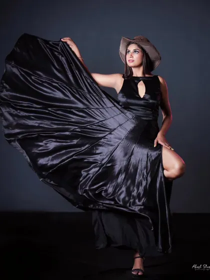 A dynamic shot of a flowing black satin gown. The model's pose and the movement of the fabric create a sense of drama and elegance for this designer piece.