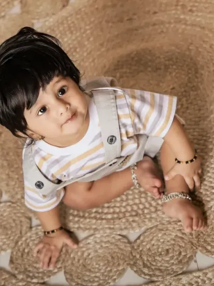 An overhead shot capturing a sweet, curious look. The textures of the jute rug add visual interest to the portrait.