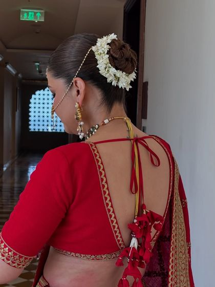 A traditional bridal updo featuring a classic gajra of fresh jasmine flowers. I created a clean, rounded bun to serve as the perfect base for the fragrant floral garland, a timeless choice for any Indian wedding ceremony.