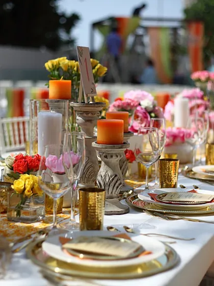 A vibrant and colourful table setting for a daytime event, with bright orange candles and multi-hued floral arrangements. This shows our versatility in creating different moods through decor.