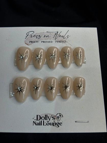 A chic and simple press-on set with a nude base and a silver starburst design on each nail.
