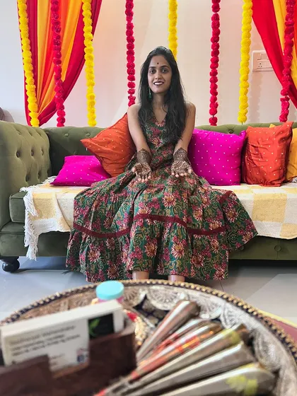 A happy client in a festive setting, showing her hands adorned with my intricate mehendi.