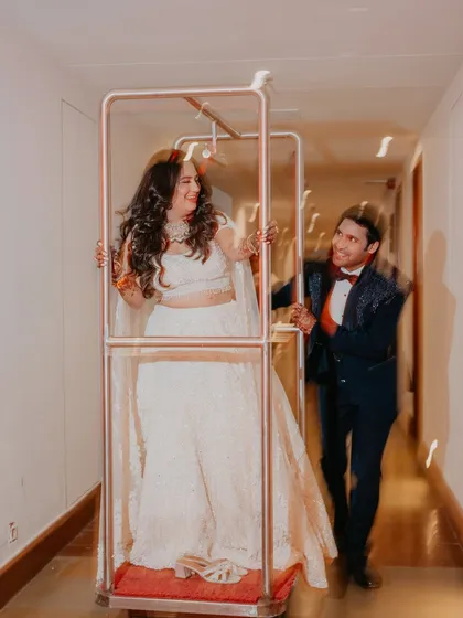 A playful moment from the Sangeet night. The groom pushes the bride on a luggage cart, a fun and quirky shot that shows their lighthearted and joyful relationship.