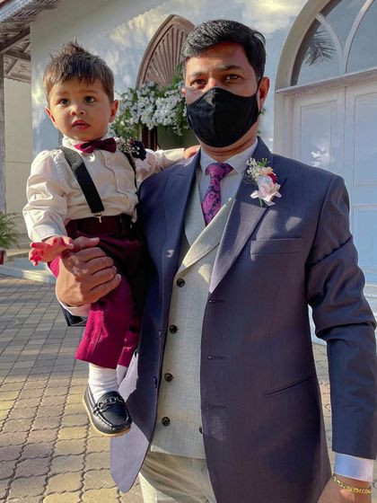 A father and son duo looking sharp for the wedding. The father wears a custom floral pin, and the little page boy has a matching bow tie, showing how accessories can coordinate the whole family.