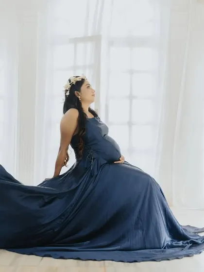 An artistic indoor shot with the blue gown's train creating a wave of fabric, set against a bright, airy background.