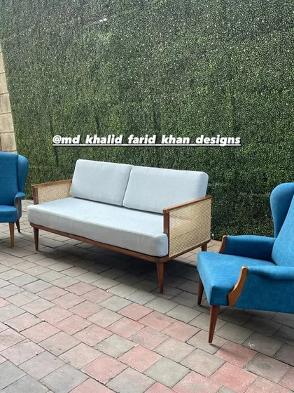 A living room set featuring a caned sofa and two blue wingback chairs.