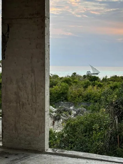 A traditional dhow sails past as seen from one of the unfinished rooms at Kizikula. Our design ensures that even from within the buildings, you feel a constant connection to the sea and the local culture.