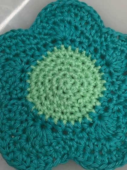 A close-up of one of the flower coasters, showing the two-tone color design and neat spiral stitching in the center.