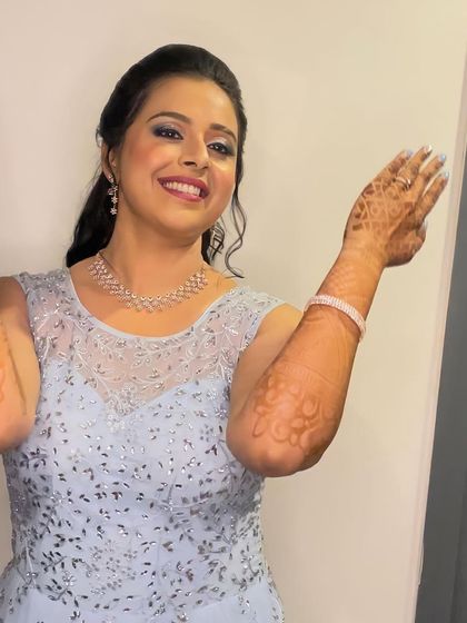 A fun and joyful moment captured during a Sangeet. The makeup features a pop of blue on the eyes to match her gown, paired with a playful high ponytail, perfect for a night of dancing.