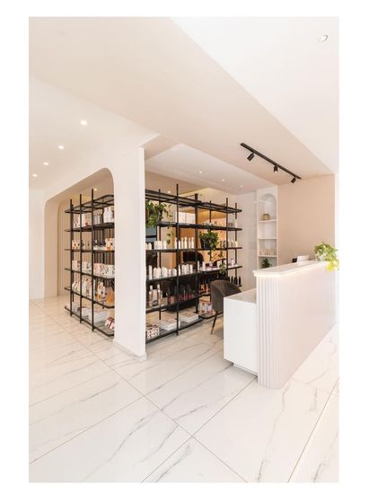 The reception and retail area of the salon, designed as a single, cohesive unit. The archway frames the view into the main service area.