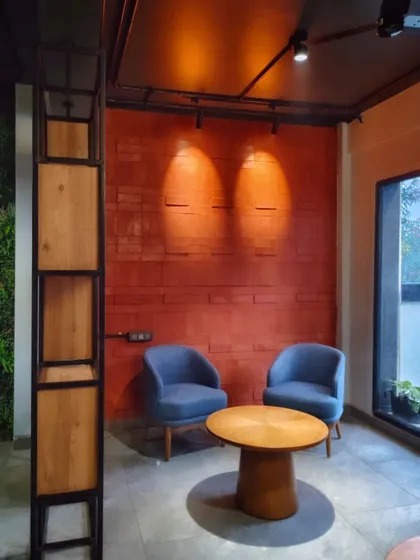 We believe every office needs a comfortable escape. This cozy breakout corner, with its warm accent lighting and comfortable seating against a textured brick wall, provides a quiet space for informal chats or focused individual work.