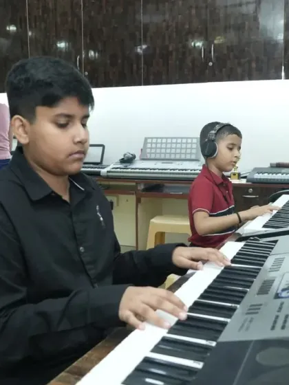 Two young students deeply focused during their keyboard class. We foster an environment where students can learn together, inspiring each other while mastering instruments like the piano and keyboard with modern training techniques.