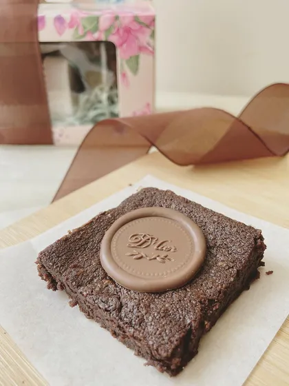 Our signature fudgy brownie, adorned with a chocolate seal, is a simple yet sophisticated treat. It's a perfect addition to any gift hamper.