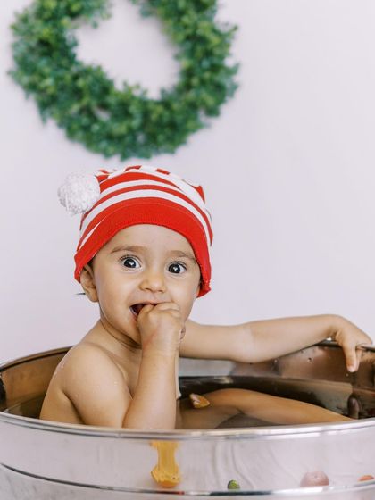 A happy baby in a Christmas-themed bathtub session. A fun and unique way to celebrate the holidays.