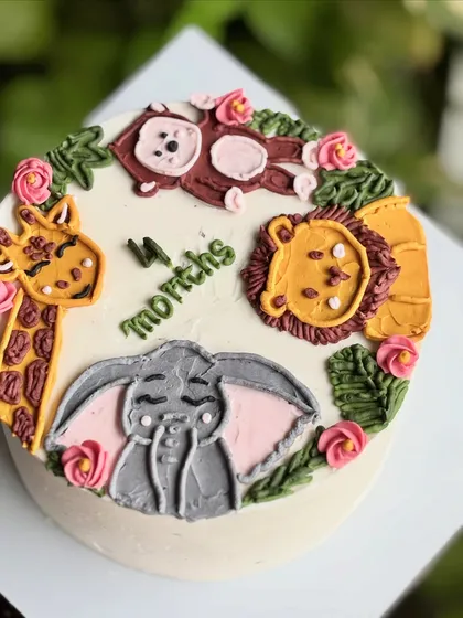 Four months of growing wild! This milestone cake features hand-piped jungle animals like a giraffe, monkey, lion, and elephant to celebrate a tiny milestone.