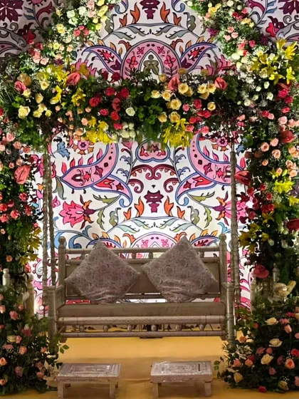 A detailed shot of the Mehendi swing setup, highlighting the intricate floral work and the colorful, traditional printed background.