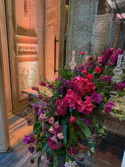 A lush arrangement of pink hydrangeas and other florals sits by a mirrored wall, reflecting the beauty and amplifying the sense of abundance.