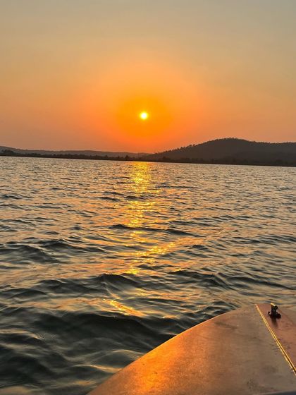The sun setting over the hills, viewed from a boat on the water. A perfect golden hour moment.