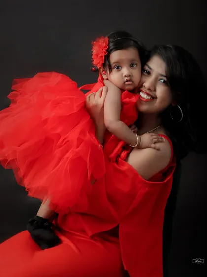 A beautiful portrait of a mother holding her baby girl, both dressed in vibrant red. Their matching outfits and close embrace make for a lovely and memorable photo.