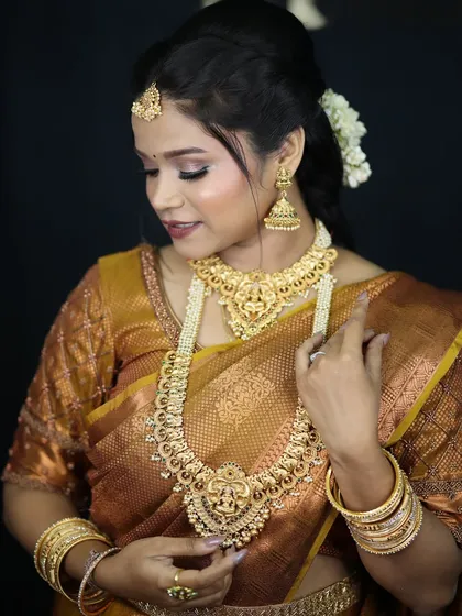 A classic South Indian bridal look. The makeup is kept warm and golden to match the traditional gold jewelry and the rich texture of the silk saree.