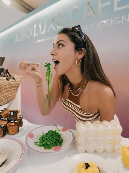 A guest enjoying a plate of our vibrant green pasta at the Ajio Luxe Café. This candid shot captures the fun and deliciousness of our fashion-inspired menu.