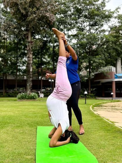 Providing gentle support for an expecting mother during her prenatal yoga practice. Here, an instructor helps her safely practice a supported headstand, modifying the pose for pregnancy.