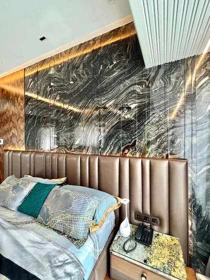 We love mixing exquisite materials to create wonderful spaces. This bedroom headboard combines a plush, channel-tufted leather panel with a dramatic, book-matched dark marble backdrop for a truly bespoke look.