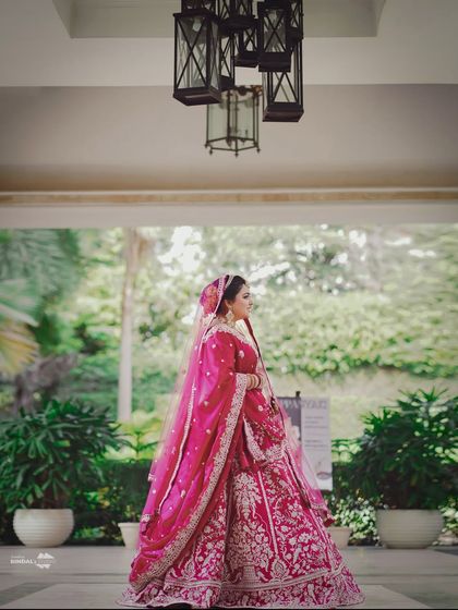 A majestic portrait of the bride in her stunning pink lehenga. The grand setting and her poised stance create an image of pure elegance and regality.